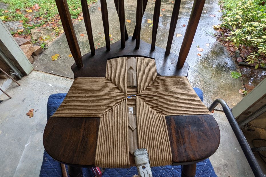 weaving fibre rush into antique chair.